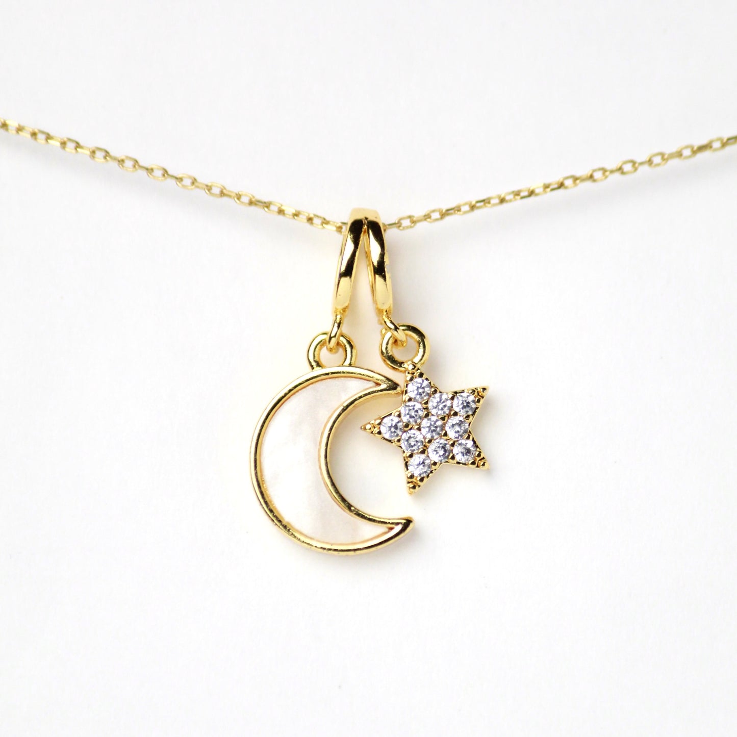 Dije dúo que representa equilibrio y magia. La luna, con su suave madreperla, y la estrella brillante de Zirconias, se unen en un diseño delicado, Oro laminado