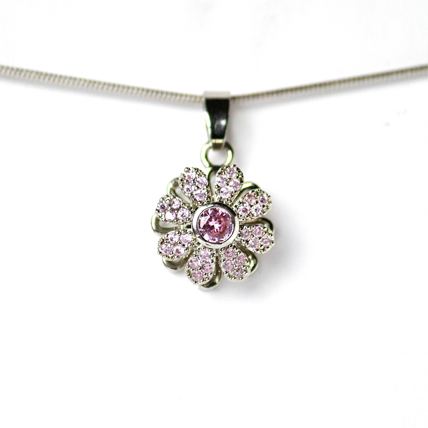 Dije de flor con Diamante central color Rosado, petalos definidos con incrustaciones de Zirconias, Acero Inoxidable