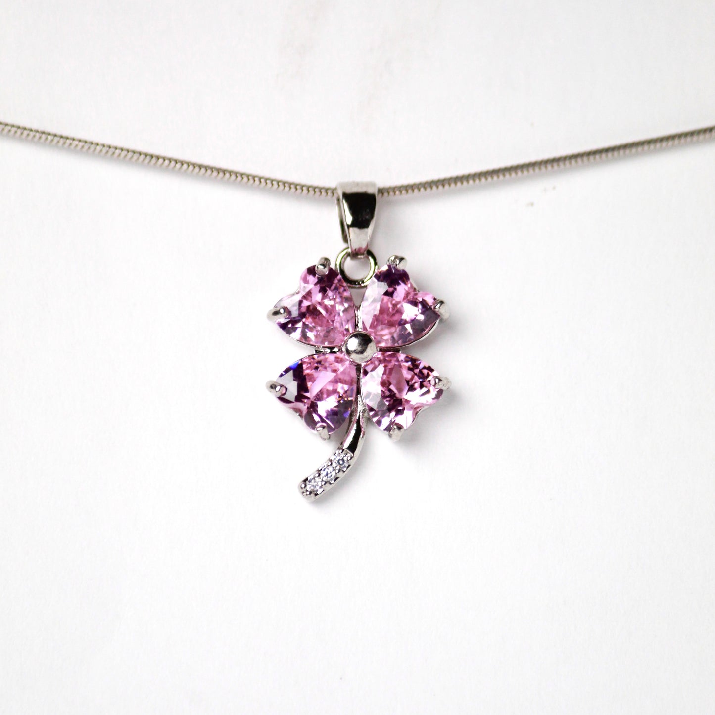 Dije de Trebol con hojas de Diamantes color rosado, en el tallo tiene incrustaciones de Diamantes brillantes, Acero inoxidable